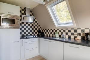 a kitchen with white cabinets and a window at Houtduif I Huisje met Omliggende Tuin in Zwiggelte