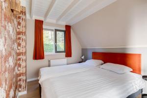 a bedroom with a large white bed with red curtains at Houtduif I Huisje met Omliggende Tuin in Zwiggelte +42 photos