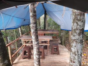 a wooden table and bench under a blue tent at Rustic Campsite Kalutara South in Kalutara
