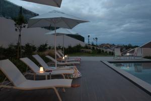 eine Gruppe von Stühlen und Sonnenschirmen neben einem Pool in der Unterkunft Vila Marta - Canário da Terra in Vila Franca do Campo