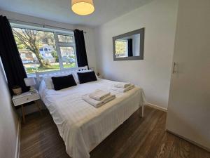 a bedroom with a bed with white sheets and a window at 2 Bed Coastal Bungalow - Millendreath, Looe in Looe