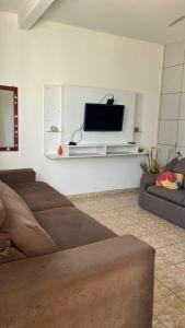 Una sala de estar con un sofá y un televisor en una pared. en Pé na areia Beach House, en Fundão