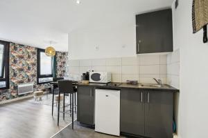 a kitchen with black cabinets and a counter top at Bluestay 144 - Charming apartment in Asnieres in Asnières-sur-Seine