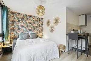 a bedroom with a large white bed and a kitchen at Bluestay 144 - Charming apartment in Asnieres in Asnières-sur-Seine