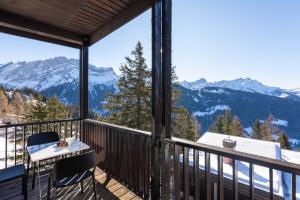 a balcony with a table and chairs and mountains at Hunter Lodge by Gryon Confort in Gryon