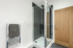 a glass shower in a bathroom next to a wooden door at The Old Embassy by Guestz in Hull +175 photos