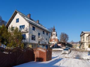 a house with a fence in the snow at Go2Krynica - Zielony PitStop in Krynica Zdrój