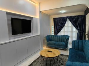 a living room with two blue chairs and a television at Newstar Jacuzzi Homestay Near Jonker Kota Laksamana Melaka in Melaka