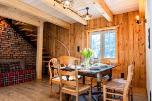 a wooden dining room with a table and chairs at Dom nad Potokiem z sauną in Lipowa