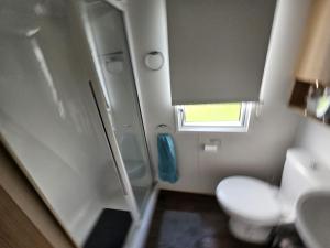 a small bathroom with a toilet and a window at Heidi 2 Bed Robin hood in Rhyl
