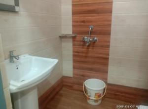 a bathroom with a sink and a trash can at Priya Hotel in Faizābād
