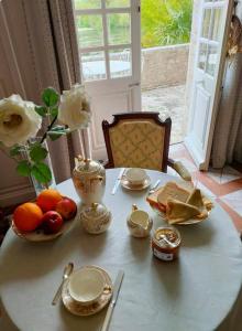 a table with fruits and plates and a vase with roses at Le Galet in Saint-Dyé-sur-Loire
