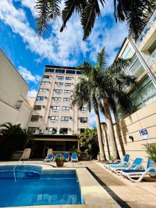 a hotel with chairs and palm trees and a pool at Condado Hotel Casino Goya in Goya +25 photos