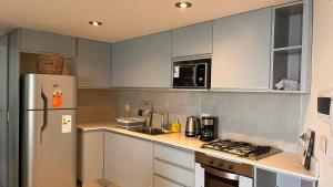 a kitchen with white cabinets and a refrigerator at Hermoso Zona Norte Río in Rosario +11 photos