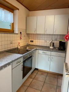 a kitchen with white cabinets and a sink at Ferienwohnung im Herzen Schönach in Herdwangen-Schönach