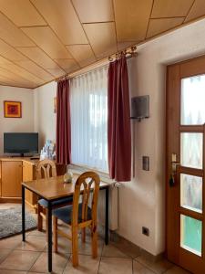 a dining room with a table and chairs and a window at Ferienwohnung im Herzen Schönach in Herdwangen-Schönach