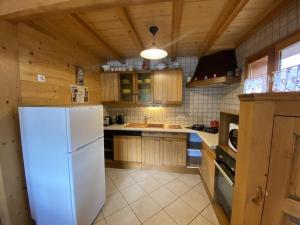 a kitchen with a white refrigerator and wooden cabinets at Chalet Le Castor : dans le centre de Chatel in Châtel