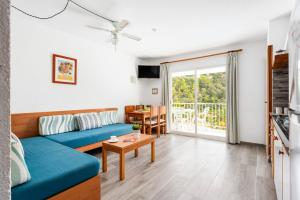 Una sala de estar con un sofá azul y una mesa. en Apartamentos Alta Galdana Playa by Escape Home, en Cala Galdana