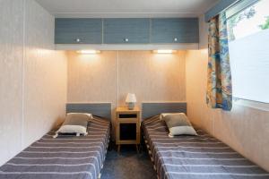Una habitación con dos camas y una mesa y una ventana. en Mobilhome Mh75 La Tremblade, en La Tremblade