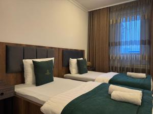 a hotel room with two beds and a window at Uniluxury Hotel Prishtina in Prishtinë