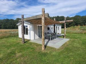 a small white cabin with a wooden roof at Hoeve Twente - De Bonte Specht in Heythuysen