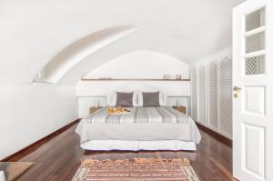 a white bedroom with a bed with a tray of oranges on it at Villa Erofili in Fira