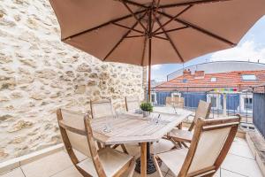 a wooden table with chairs and an umbrella on a balcony at Bar à Bulles - Ancien Comptoir Transformé in Reims