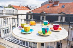 a table with four cups and saucers on a balcony at Bar à Bulles - Ancien Comptoir Transformé in Reims