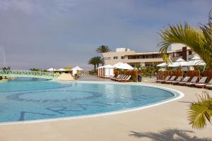 a pool at a resort with chairs and umbrellas at Aranwa Paracas Resort & Spa in Paracas
