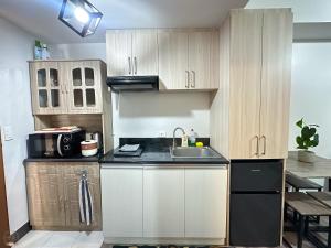 a kitchen with white cabinets and a black refrigerator at Cozy Home in Cebu City