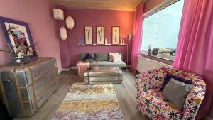 不莱梅Maison Provençale的客厅设有粉红色的墙壁、沙发和窗户