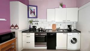a kitchen with white cabinets and a sink and a dishwasher at Maison Provençale in Bremen