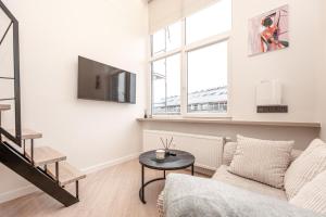 un salon blanc avec un canapé et une table dans l'établissement Cozy loft in Vilnius city center, à Vilnius