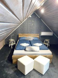 a bedroom with a bed with two white stools at Maul - Lator Présbár és Bortrezor in Villány