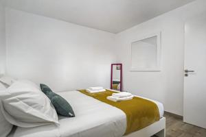 a white bedroom with a bed with towels on it at Seaside Charm I in Câmara de Lobos