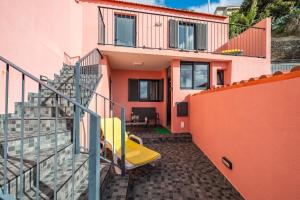 a balcony of a house with a yellow chair at Seaside Charm I in Câmara de Lobos