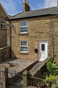 una casa in pietra con porta bianca e scale di 43 Heol Maelor- A Homely Cottage in Wrexham, North Wales a Coedpoeth