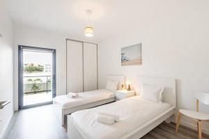 a white room with two beds and a window at Mar T2 - By Smarthomes in São Martinho do Porto +42 photos