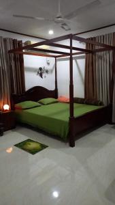 a bedroom with a canopy bed with green sheets at Villa Meghana in Galle