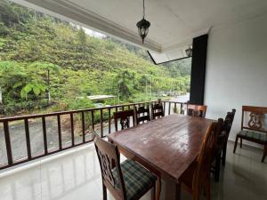 Un comedor con mesa y sillas y un balcón. en Cottage Hill -Cameron Highlands, en Cameron Highlands