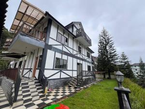 una casa blanca y negra con un patio a cuadros en Cottage Hill -Cameron Highlands, en Cameron Highlands