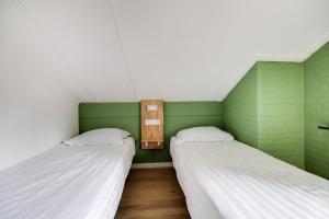 two beds in a room with green and white at Grote Bonte Specht I Moderne Bungalow aan Bosrand in Zwiggelte +44 photos