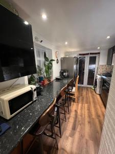 cocina con encimera, microondas y sillas en room near Luton center, en Luton