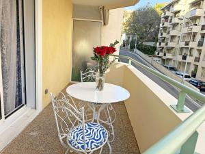 a table and chairs on a balcony with a vase of flowers at Stunning Studio Rue France Promenade des Anglais in Nice