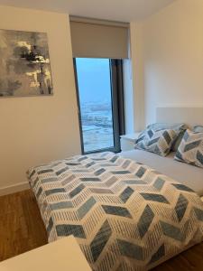 a bedroom with a bed and a large window at The Urban Escape in Media City - A private room and bathroom in a shared apartment in Manchester