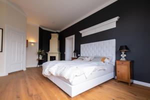 a bedroom with a white bed and a black wall at Oskar & Luise in Krummbek