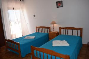 アルブフェイラにあるVila Praia Apartmentの窓付きの客室で、ベッド2台(ブルーシーツ付)