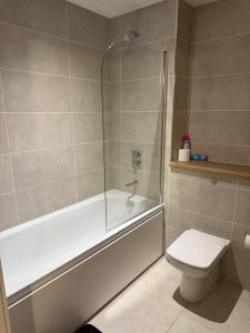 a bathroom with a tub and a toilet and a shower at The Urban Escape in Media City - A private room and bathroom in a shared apartment in Manchester