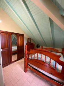 une chambre avec un lit en bois dans une pièce dans l'établissement Appartement de type T4, à Capesterre