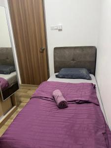 a bed with a purple blanket on top of it at Jin Lin Homestay 1 in Sibu